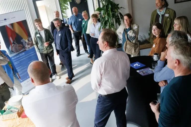 Deltagere fra dansk og tysk erhvervsliv står samlet i et lokale til et Business DE-DK-arrangement