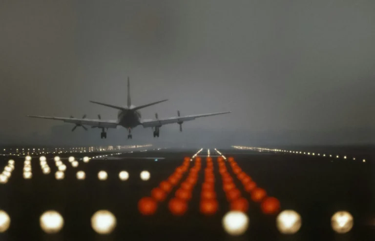 Fly lander på en oplyst landingsbane i skumringen