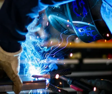 Svejser med beskyttelseshjelm arbejder på metal, mens gnisterne flyver