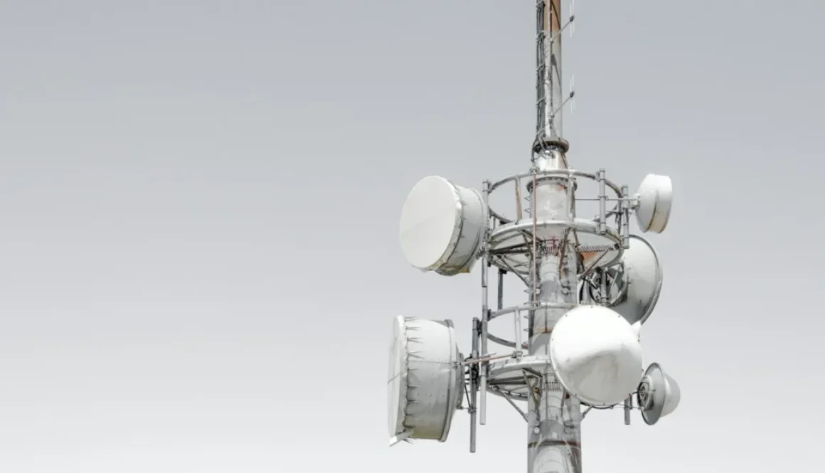 Mobilmast med antenner mod en lys himmel