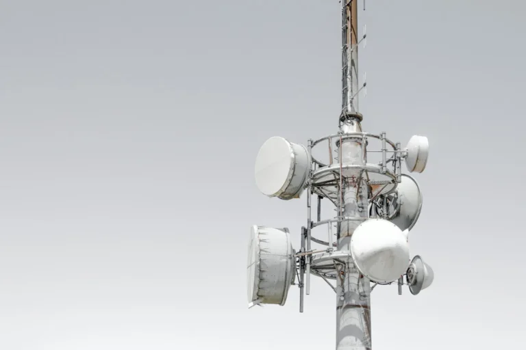 Mobilmast med antenner mod en lys himmel